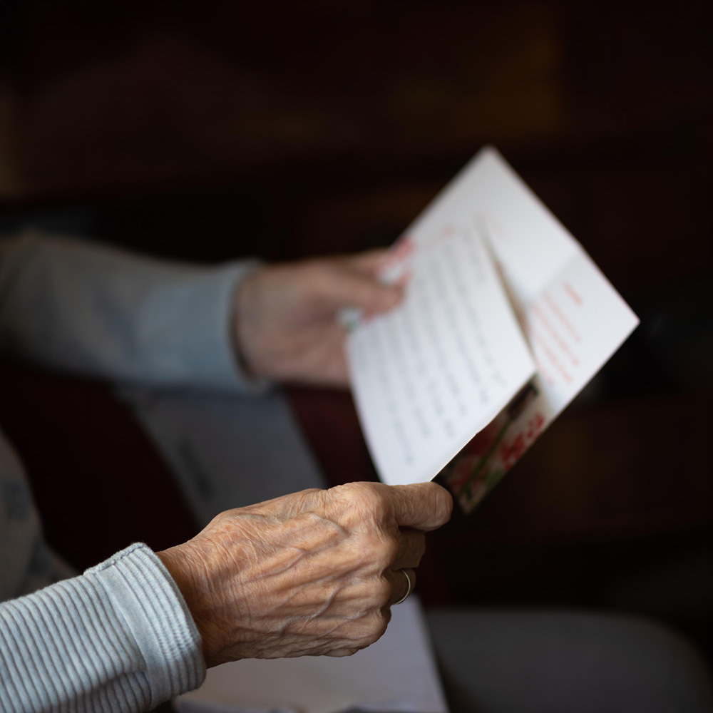 Ältere Person, die einen Text und eine Karte in Händen hält